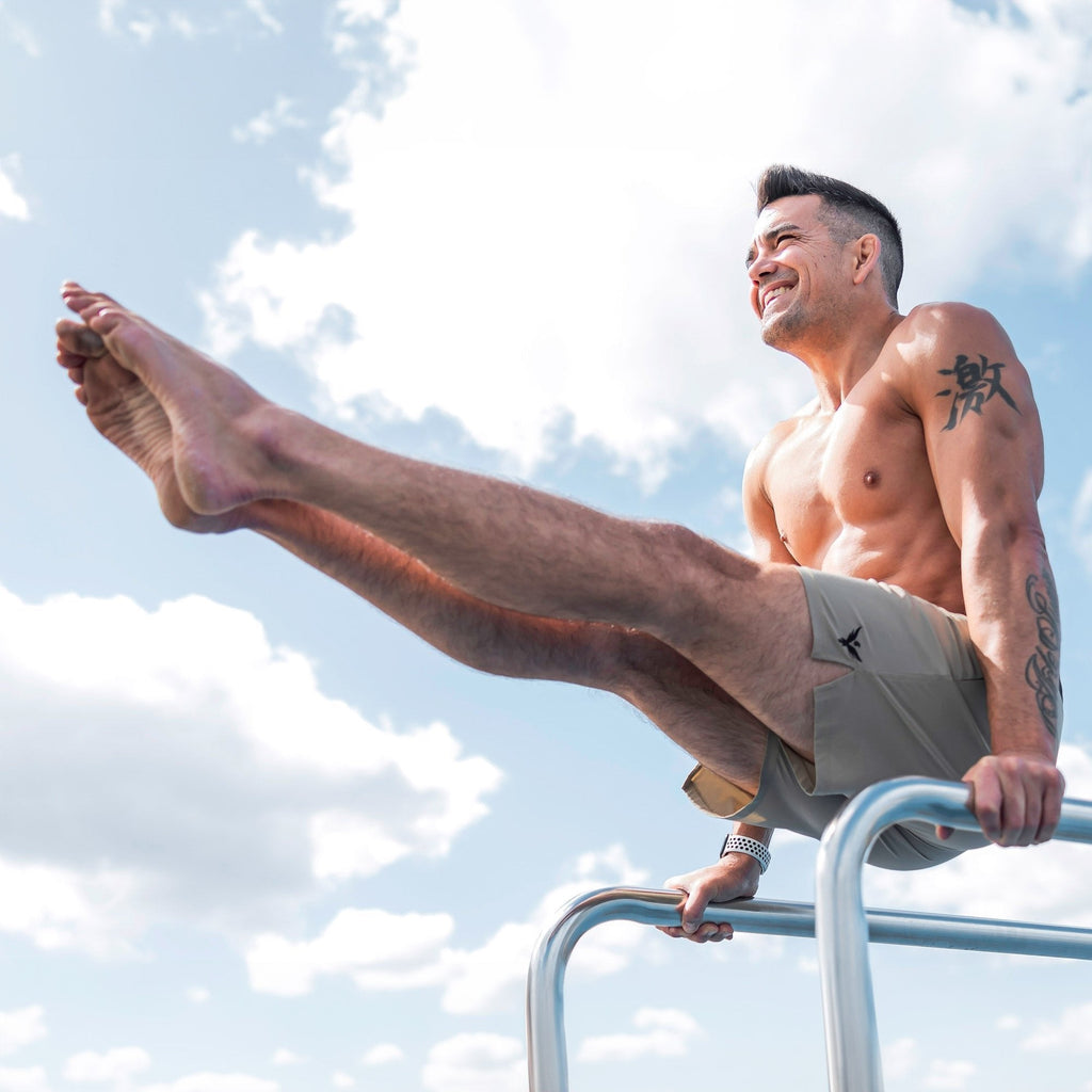 Man demonstrating movement in Flow Men's Lined Hot Yoga Shorts 5 Inch in khaki during outdoor practice.