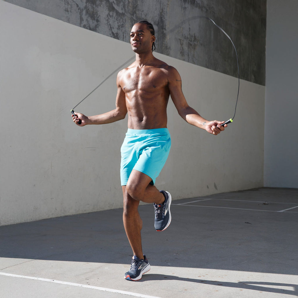 Man skipping rope outdoors wearing Swerve Men's Lined Yoga Shorts 7 Inch in Aqua Blue.