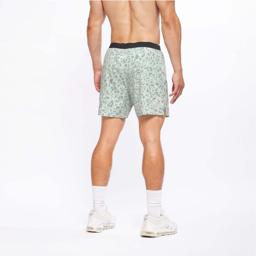 Flow shorts in lichen color showcasing the back view on a model during active movement.