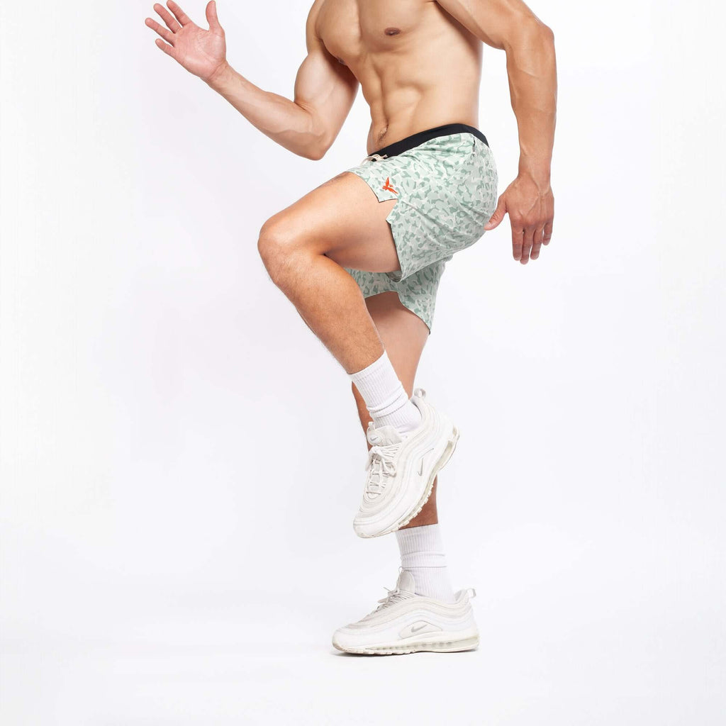 Flow shorts in lichen color worn by a man, showcasing flexibility during a workout.