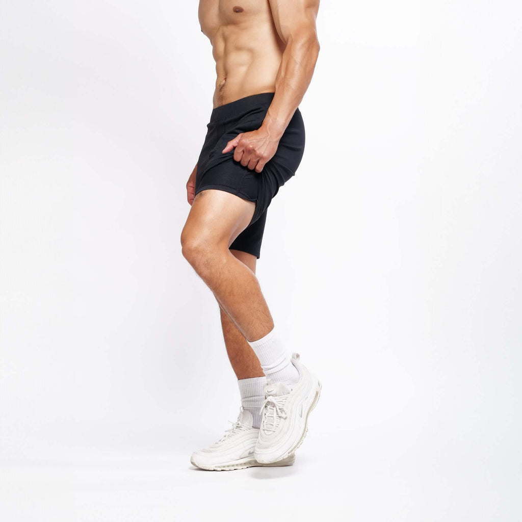 Male model showcasing 4-way stretch Swerve Shorts in Crow Black, designed for optimal movement and performance.
